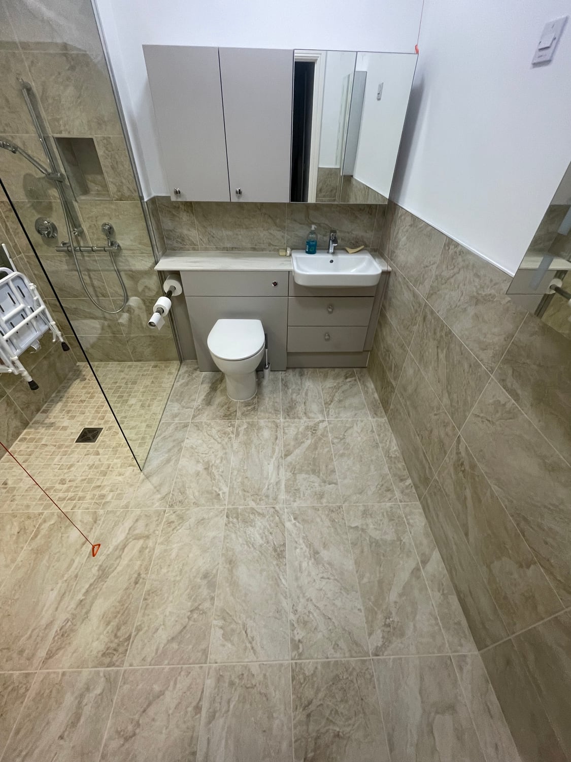 Completed light-tiled bathroom with walk-in shower and fitted storage