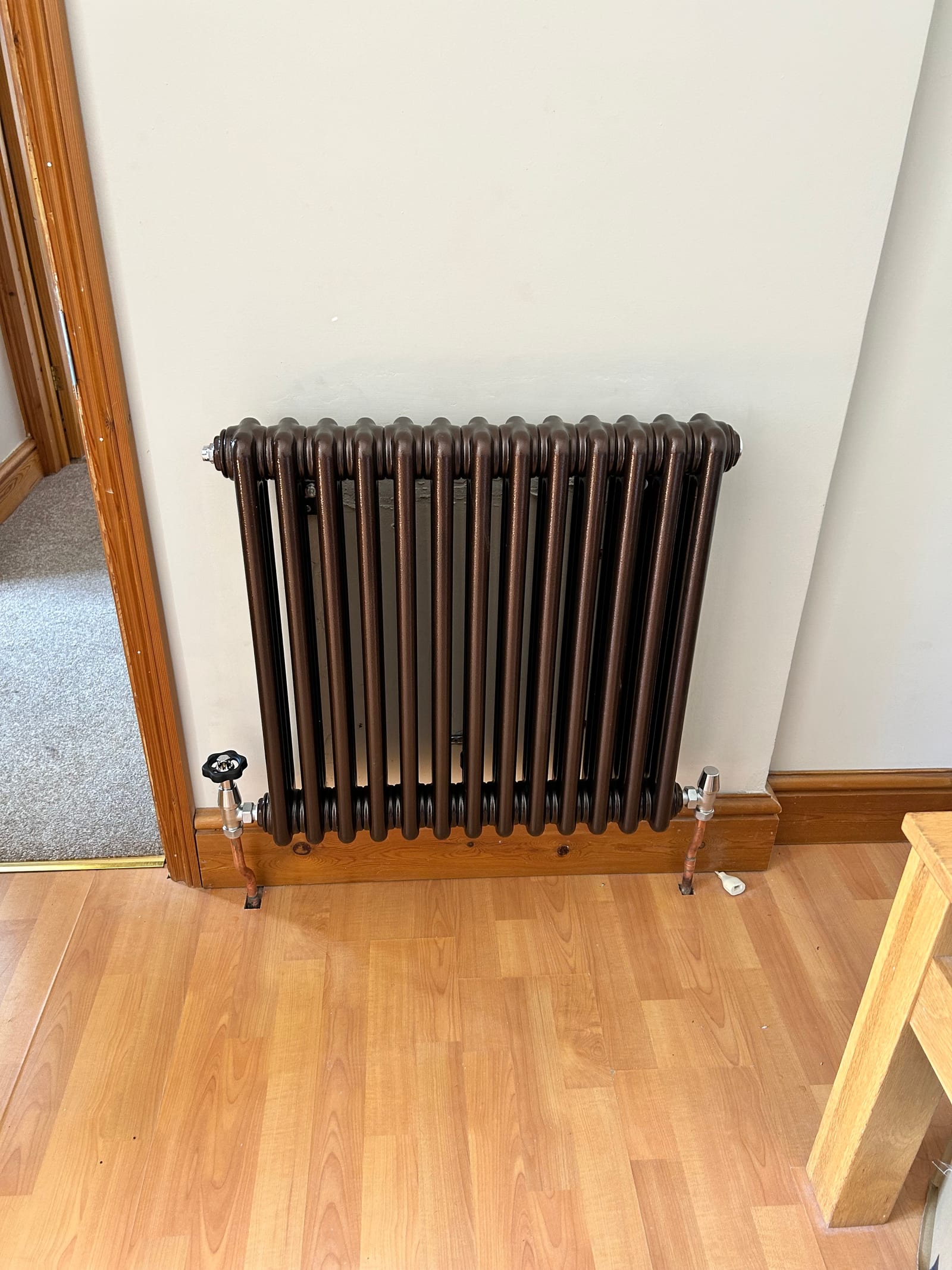 Bronze column radiator fitted against a white wall