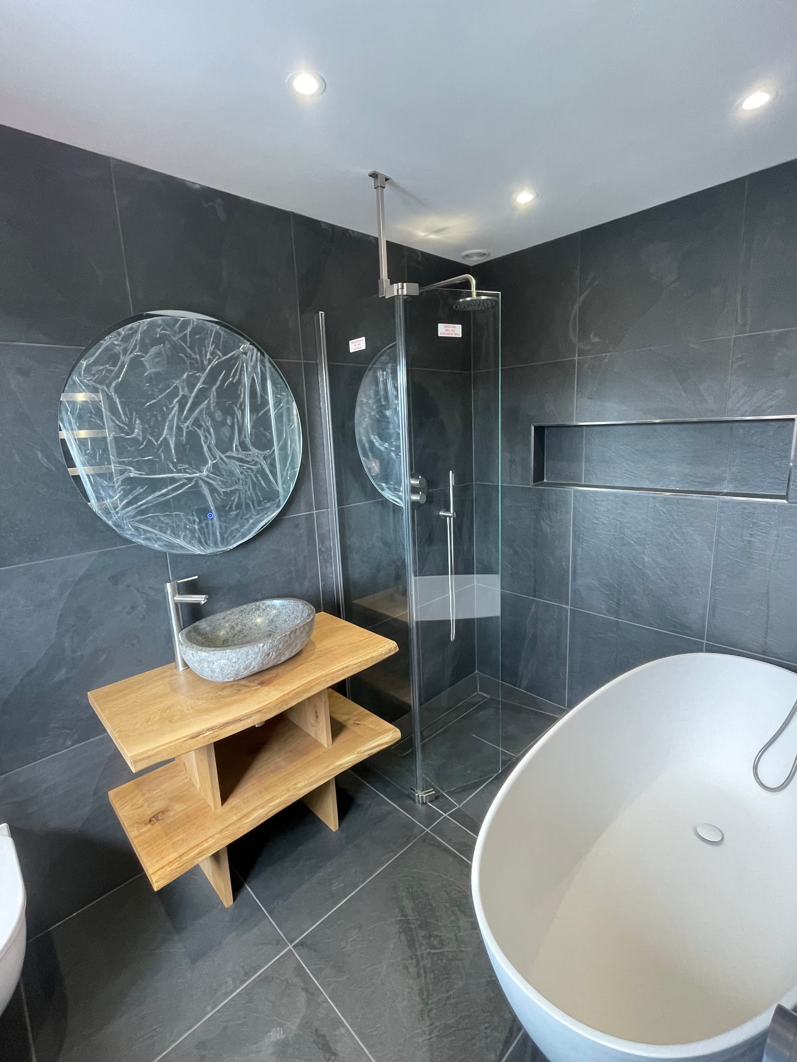 Dark-tiled bathroom with a freestanding bath and walk-in shower