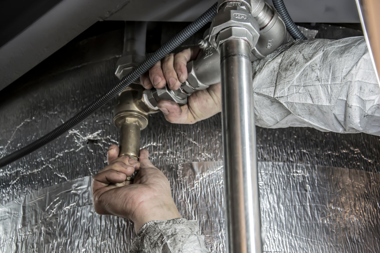 Plumber working carefully on indoor pipework